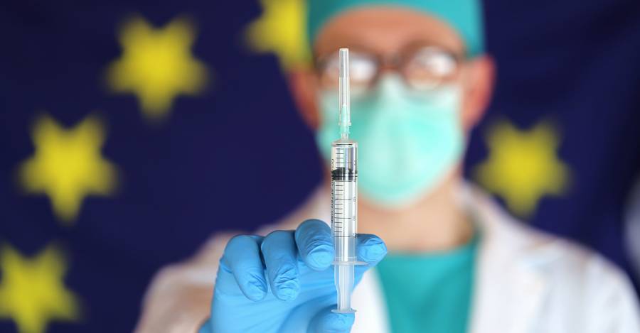 Virus vaccine. Coronavirus treatment in Europe.Virus vaccination in the European
Union.Doctor in mask with a syringe in his hands on a European flag background....